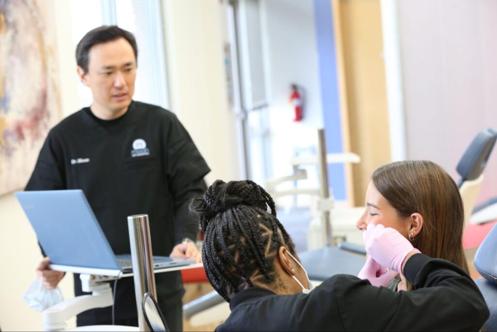 Dr. Moon consulting with a patient while an assistant performs an Invisalign check-up at Moon Orthodontics in Overland Park.